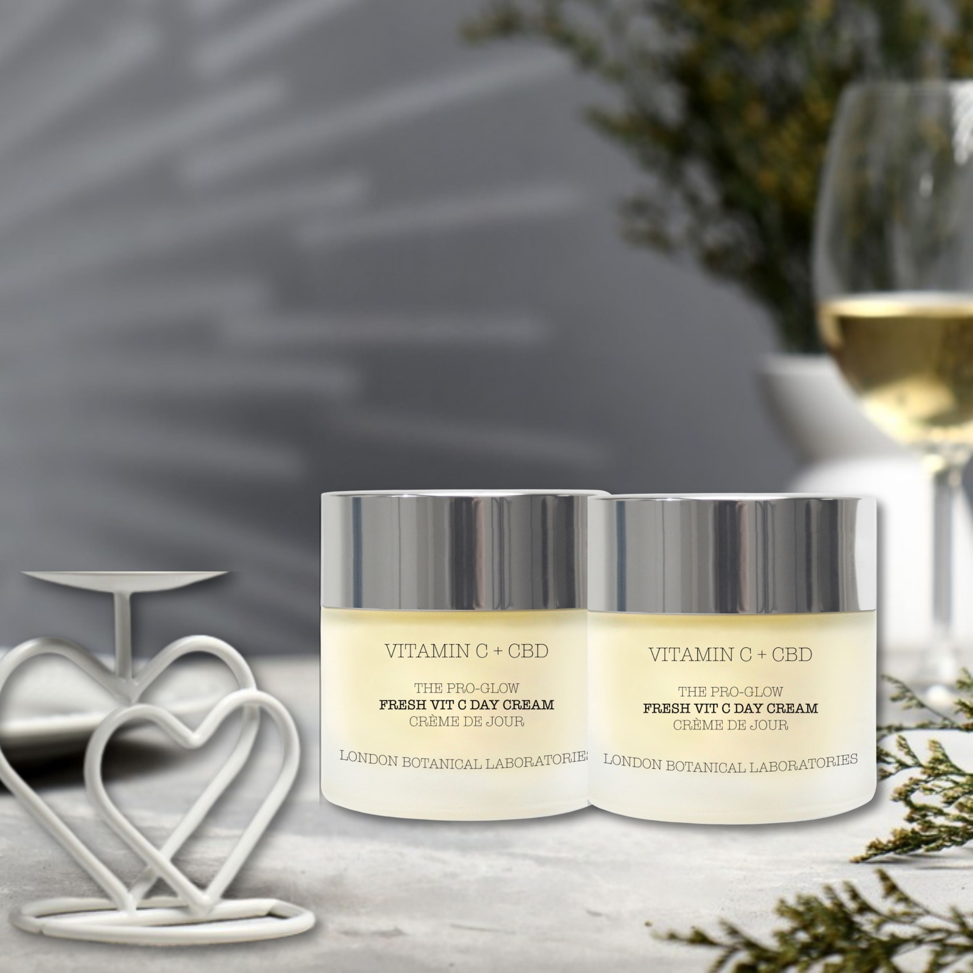 Zwei Cremetiegel mit silbernen Deckeln. Aufschrift: Vitamin C + CBD, The Pro-Glow Fresh Vitamin C Day Cream. Auf hellem Hintergrund.