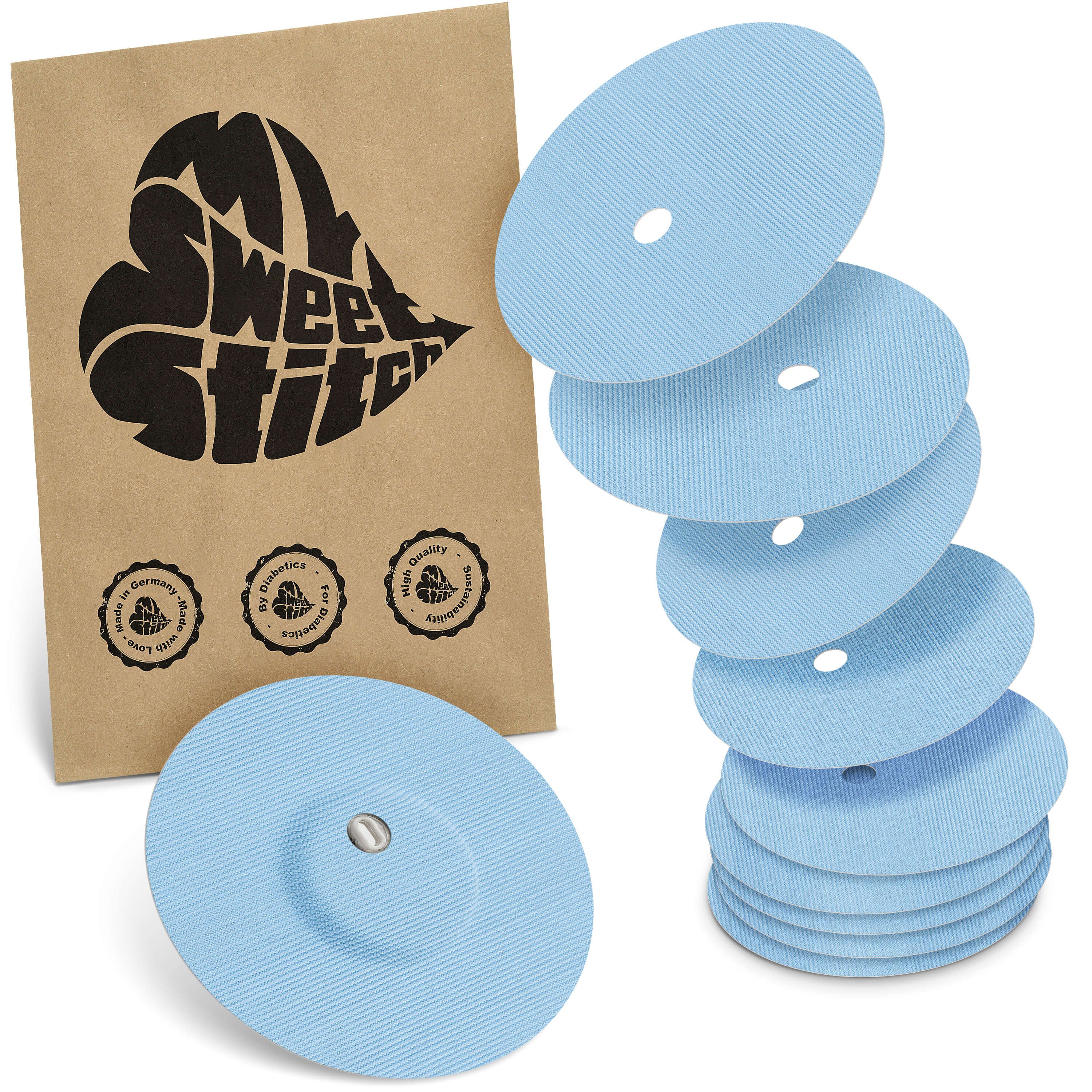 Fixierpflaster mit Belüftungsloch. Hellblaue, runde Pflaster mit zentralem Loch und Metallteil. Verpackung mit Logo.