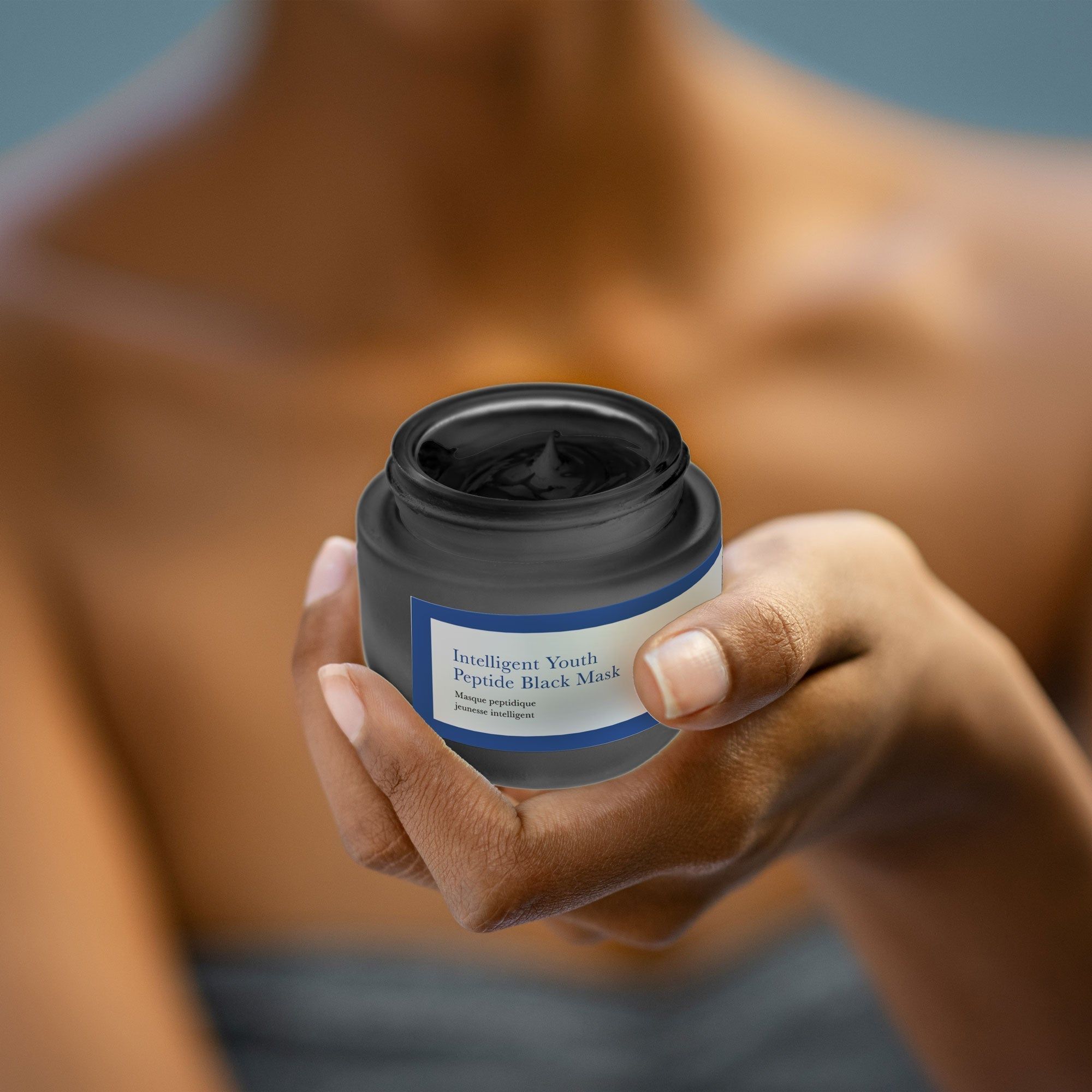 Person hält eine offene Dose. Schwarze Maske sichtbar. Aufschrift: Intelligent Youth Peptide Black Mask. Marke: skin RESEARCH.