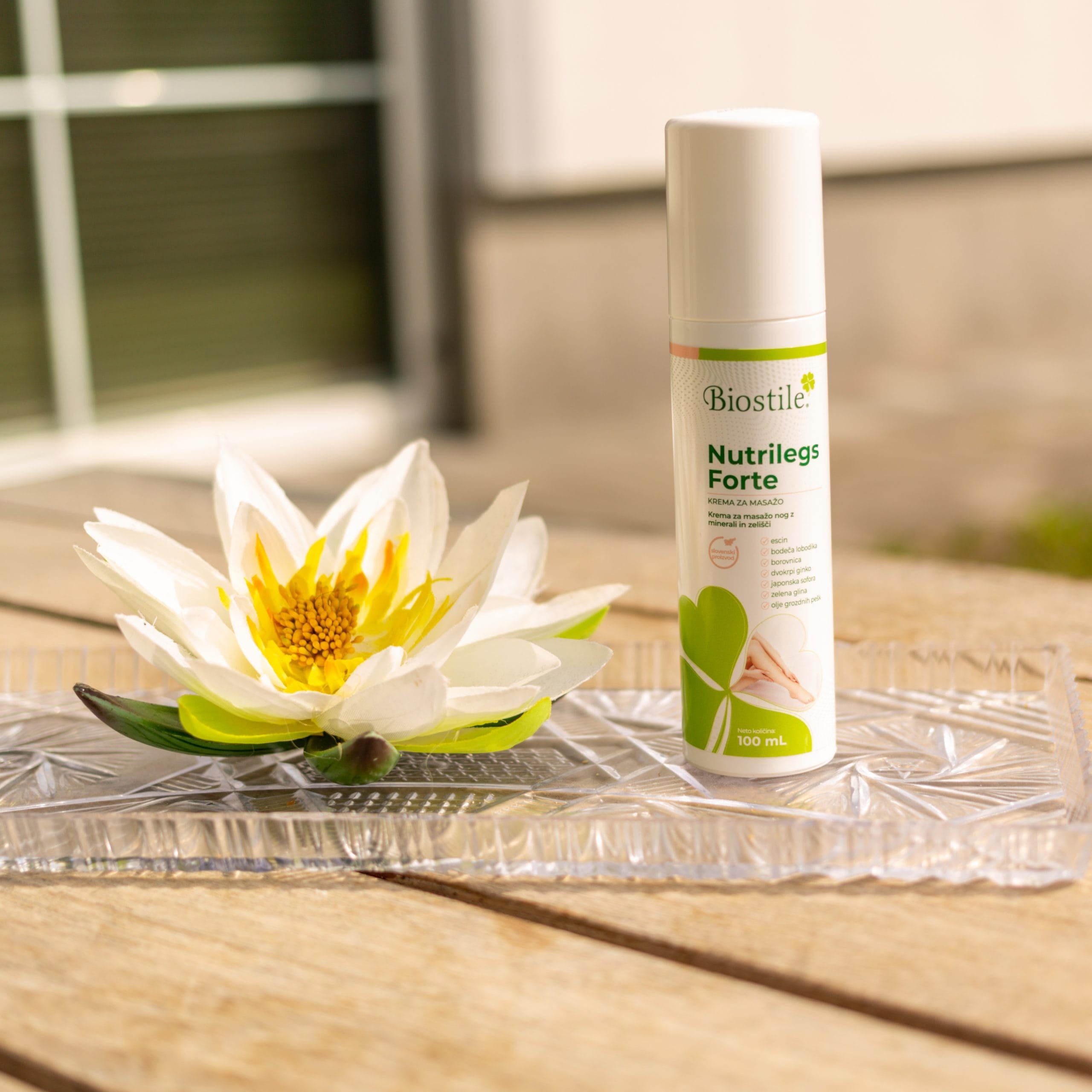 Biostile Nutrilegs Forte Creme in weißer Spenderflasche mit Lotusblüte auf Glasplatte.