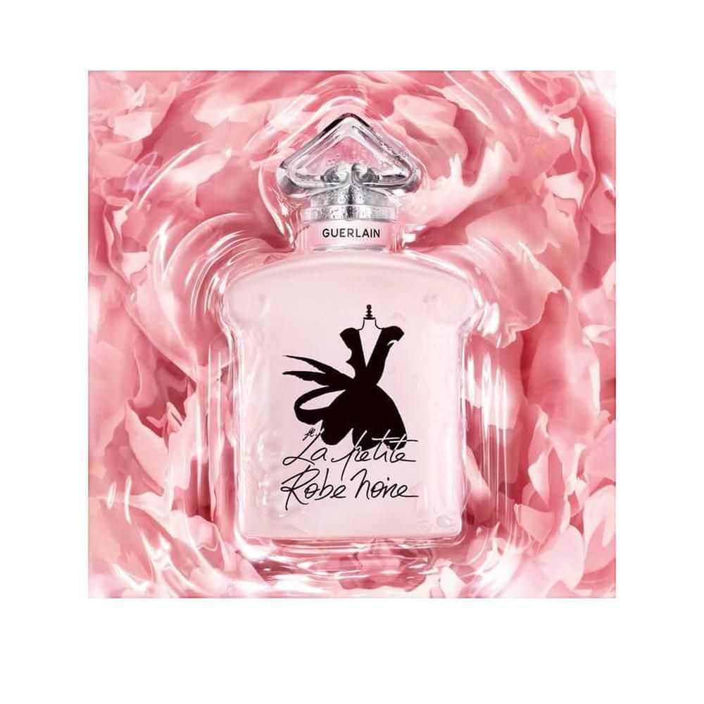 Rosa Flakon in Verpackung mit Rosenblüten. Silberner Verschluss, Schriftzug Guerlain. La Petite Robe Noire.