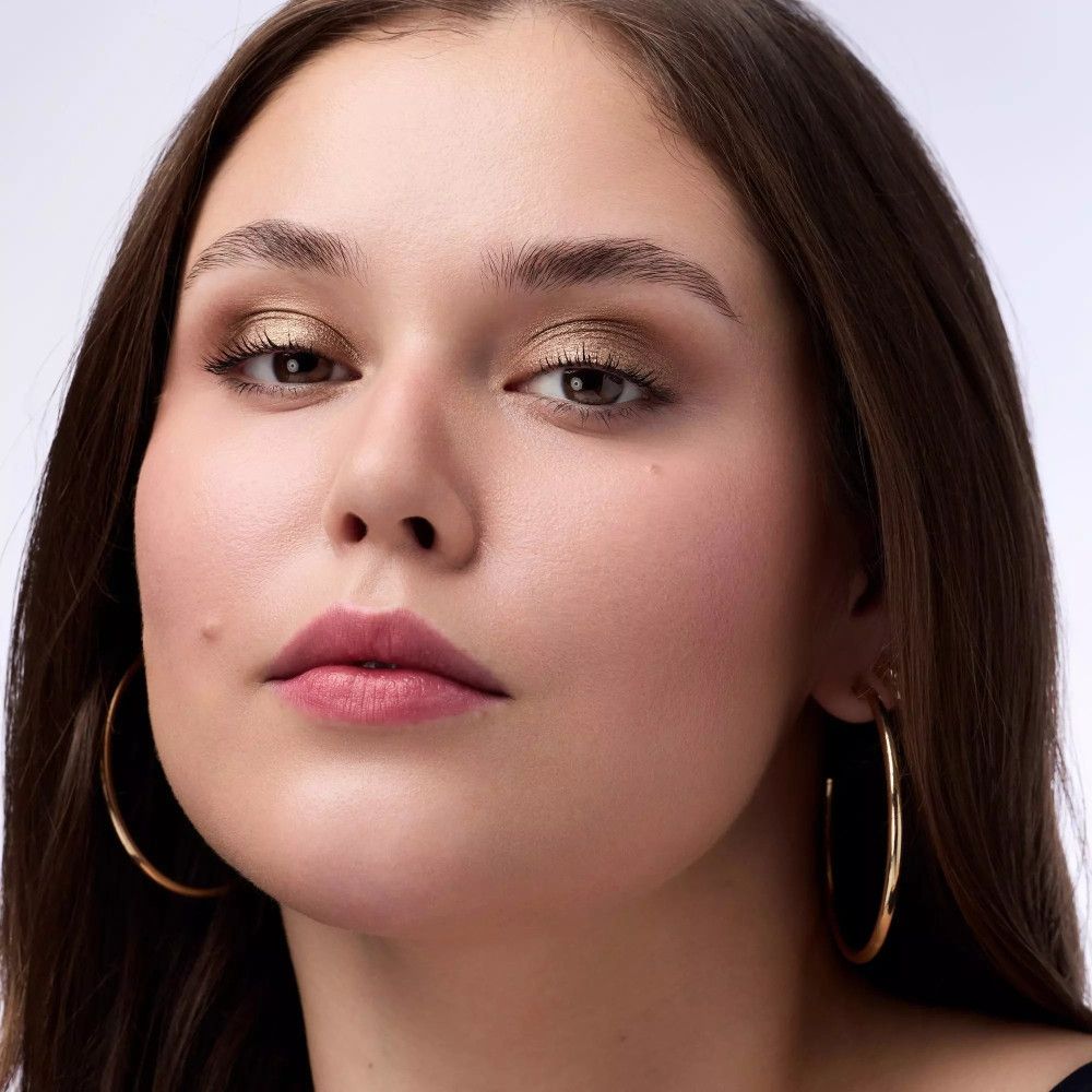 Porträt einer Frau mit goldfarbenem Lidschatten. Große goldene Creolen. Natürliches Licht.