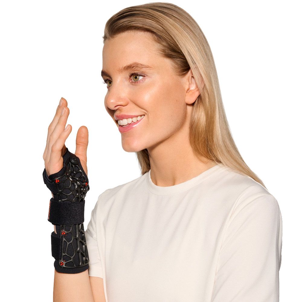 Frau trägt eine schwarze Handgelenkorthese mit offenem Gittermuster.