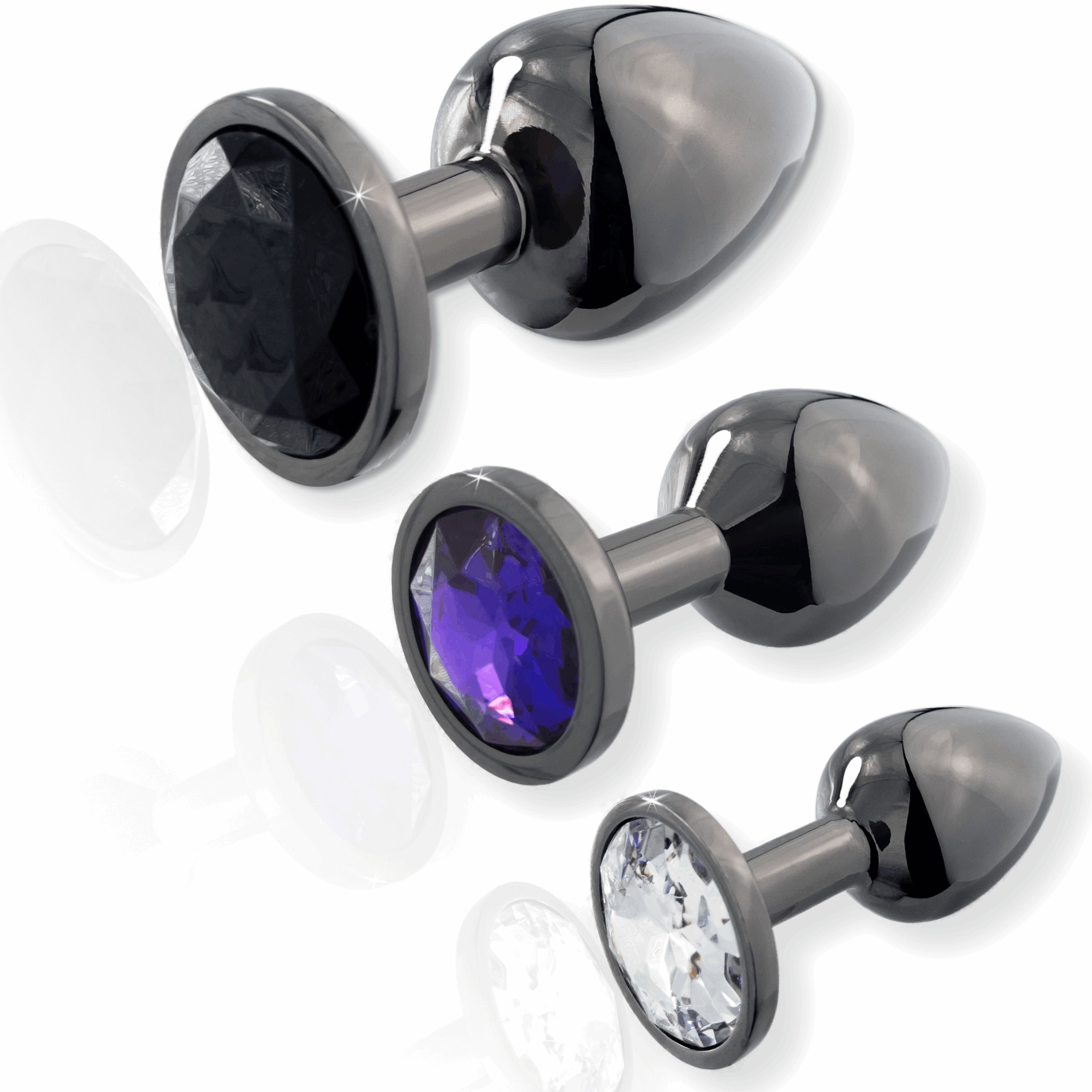 Drei Analplugs mit Edelstein-Optik. Schwarze, violette und transparente Steine. Schwarze Schäfte. Perspektivische Darstellung.