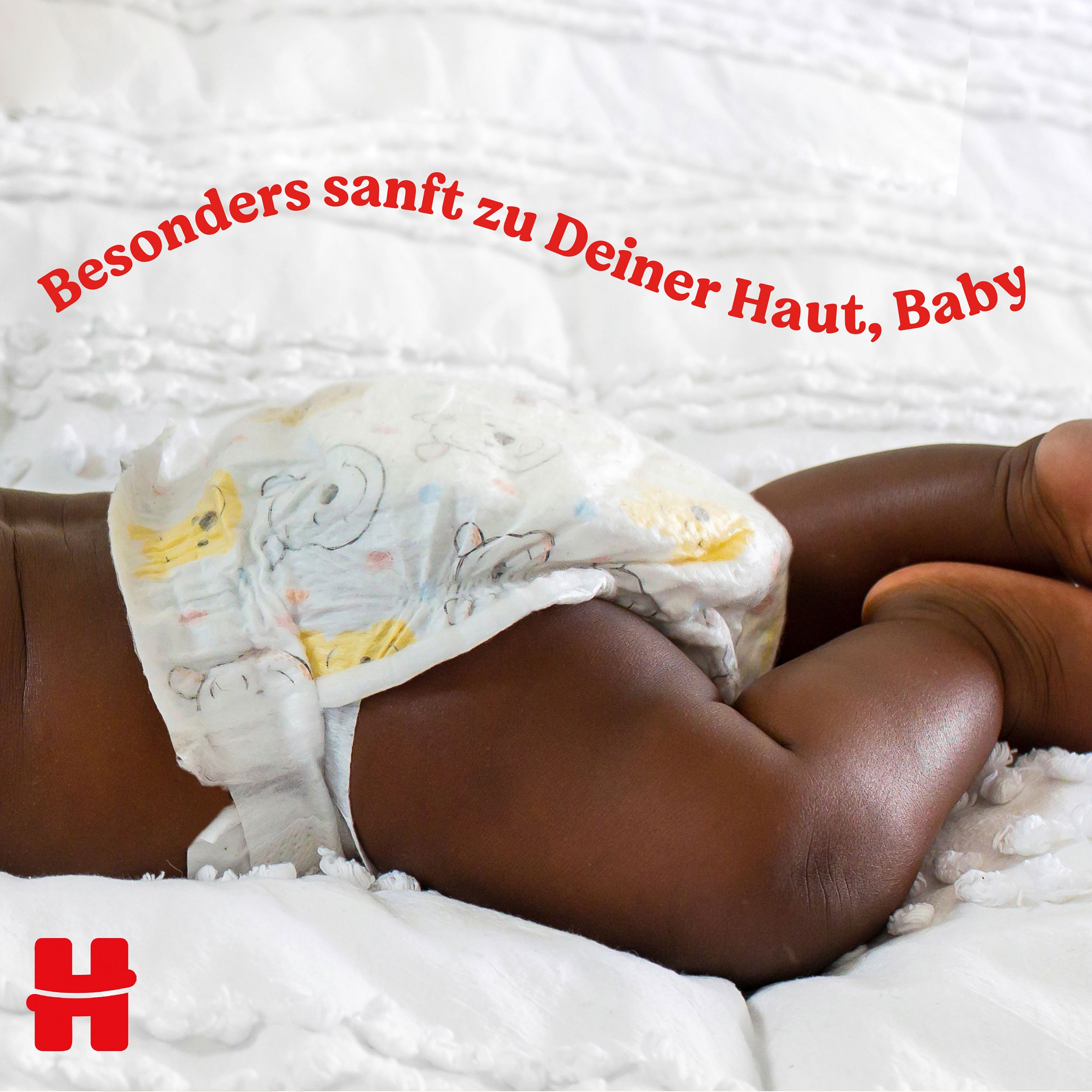 Baby liegt auf dem Bauch, Windel sichtbar. Text: Besonders sanft zu Deiner Haut, Baby. Logo 'H' unten links.