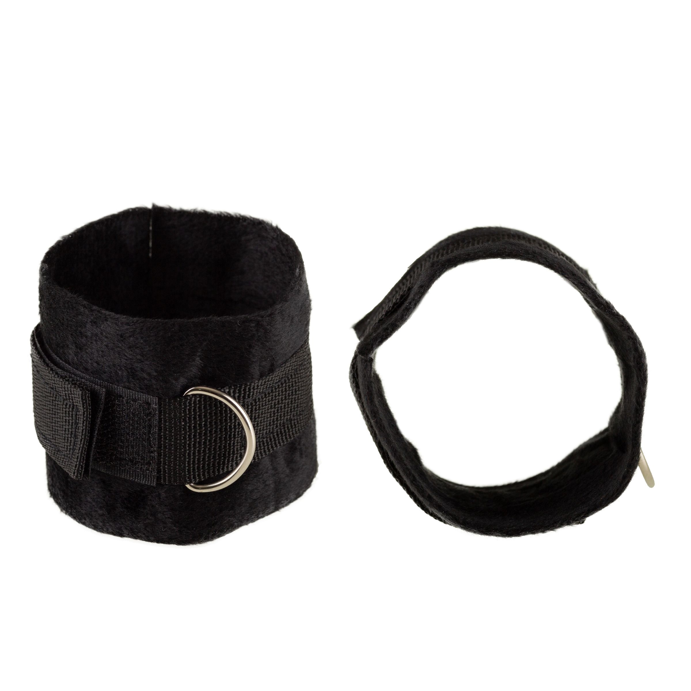 Zwei schwarze Handfesseln. Eine Manschette mit Klettverschluss und Metallring. Die andere mit einem Band und Metallring.