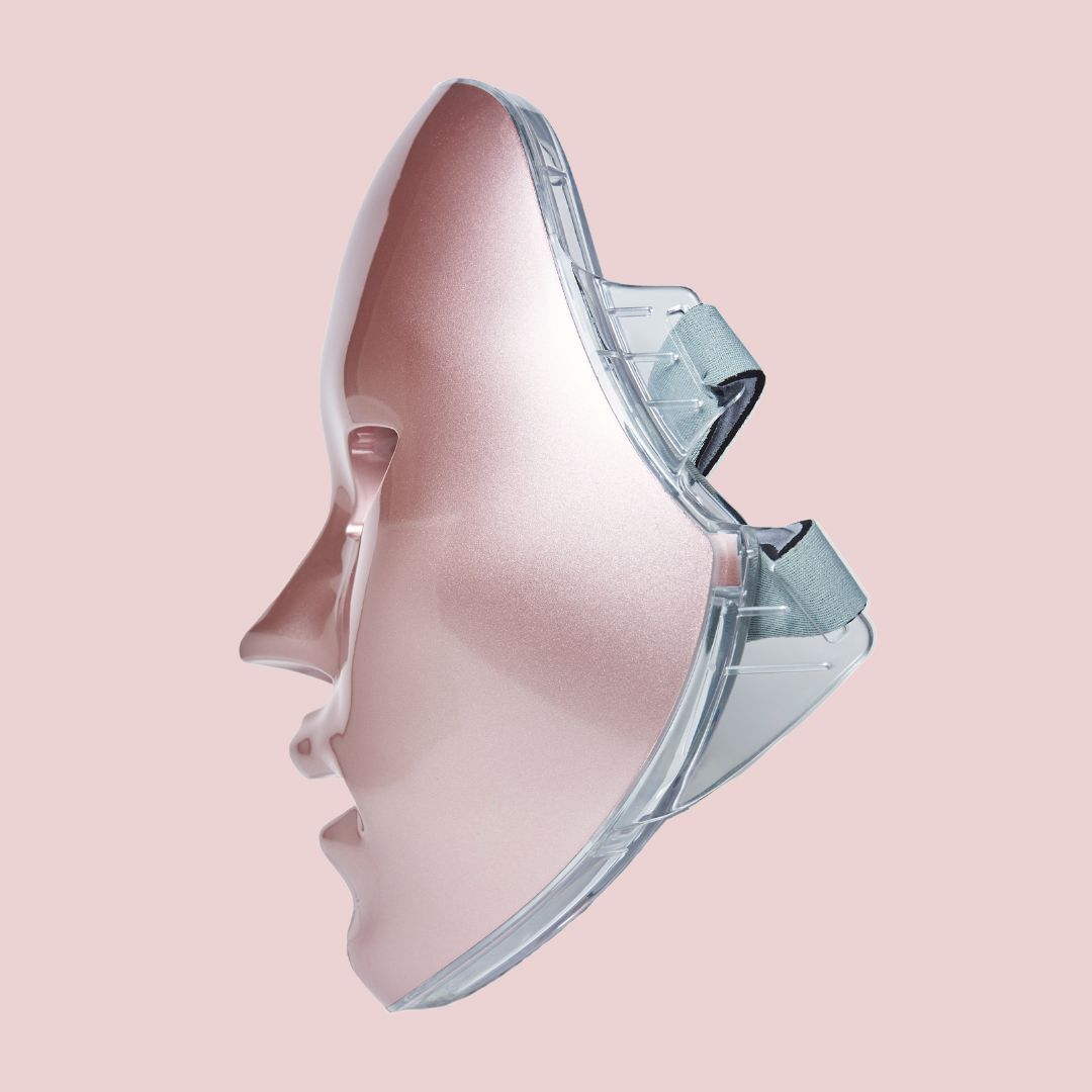 Rosafarbene LED-Gesichtsmaske mit transparenten Halterungen. Die Maske hat Öffnungen für Augen, Nase und Mund. Seitenansicht.