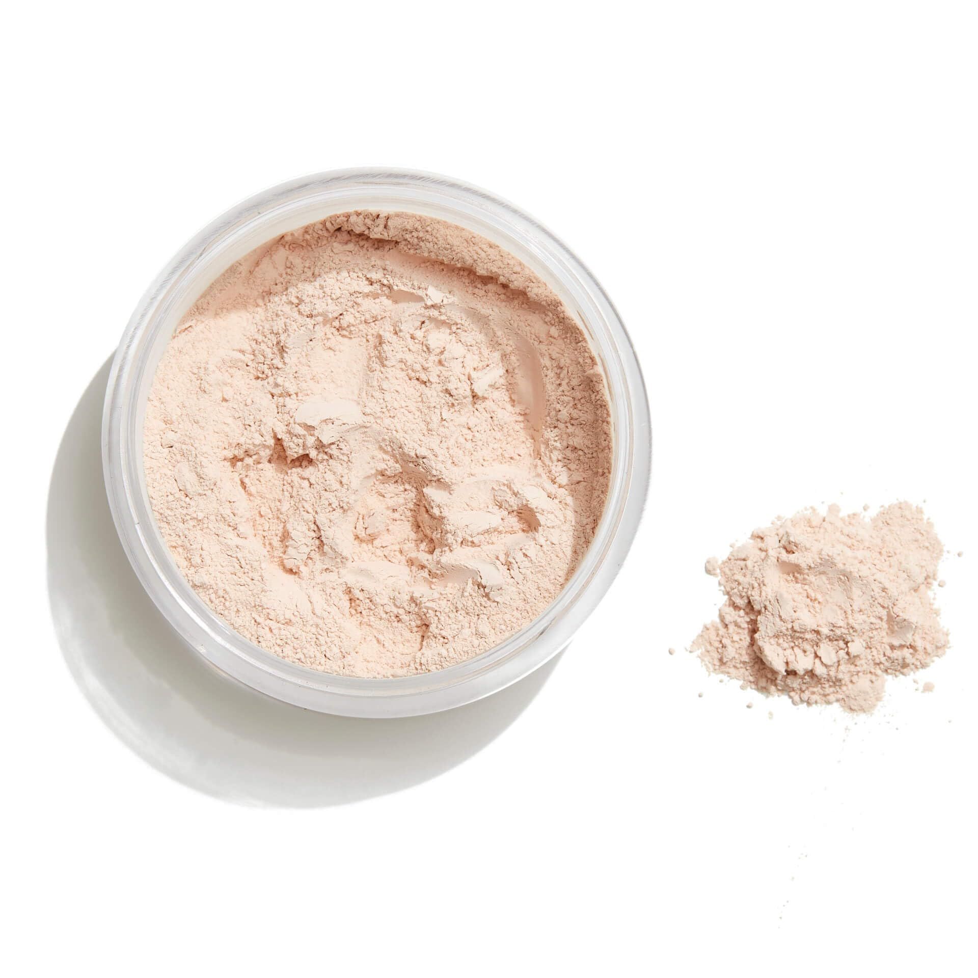 Transparenter Puder in Dose und daneben ein Haufen Puder. Auf weißem Hintergrund.