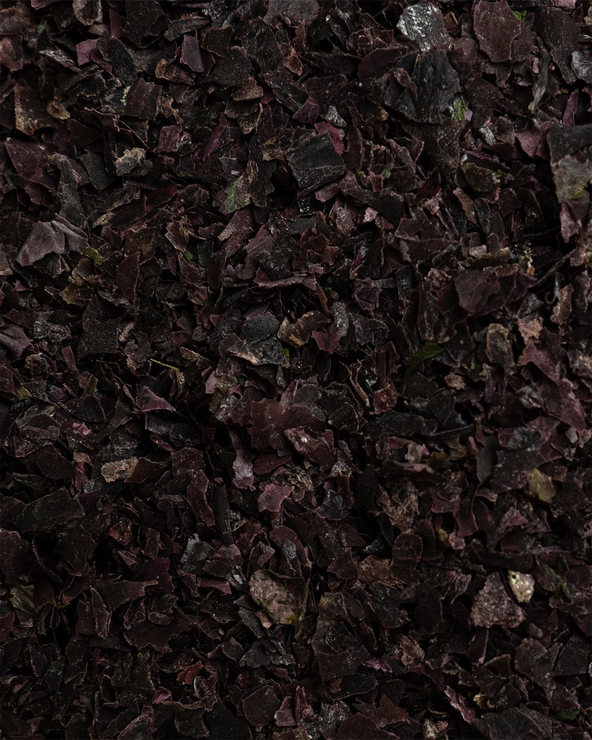 Makroaufnahme von getrockneten Bio Dulse Flocken. Dunkle, rötlich-braune Flocken mit sichtbarer Textur.