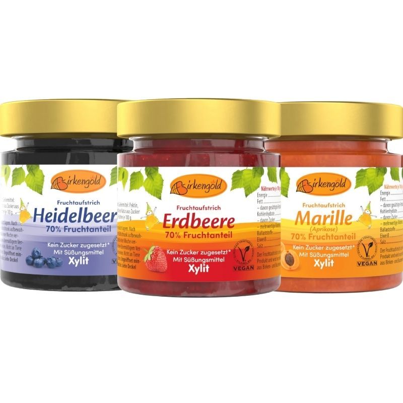 Drei Gläser Birkengold Fruchtaufstrich. Sorten: Heidelbeer, Erdbeere, Marille. Goldfarbene Deckel, Etiketten mit Produktnamen und Logo.