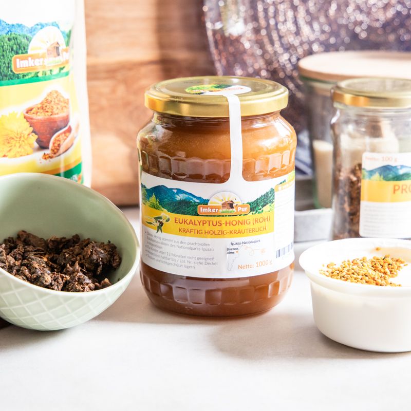 Glas Honig mit Etikett, umgeben von Zutaten. Aufschrift: Eukalyptus-Honig (roh).