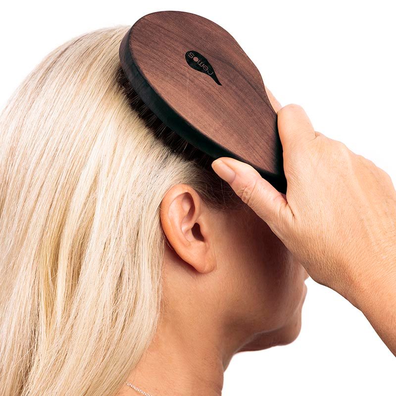 Handbürste aus Holz mit Wildschweinborsten auf blondem Haar.