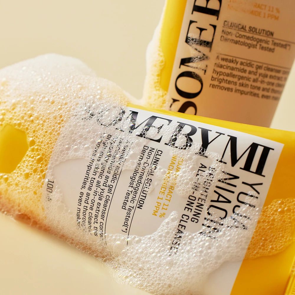 Gelbe Tube mit Aufschrift Yuja Niacin Brightening All-in-One Cleanser, umgeben von Schaum. Text: Dermatologisch getestet.