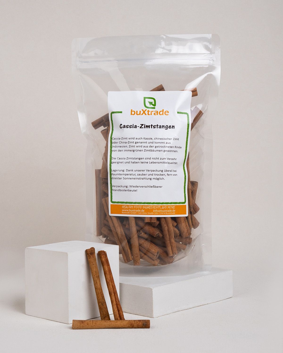 Ein Beutel mit Cassia-Zimtstangen von buxtrade, daneben drei einzelne Stangen.
