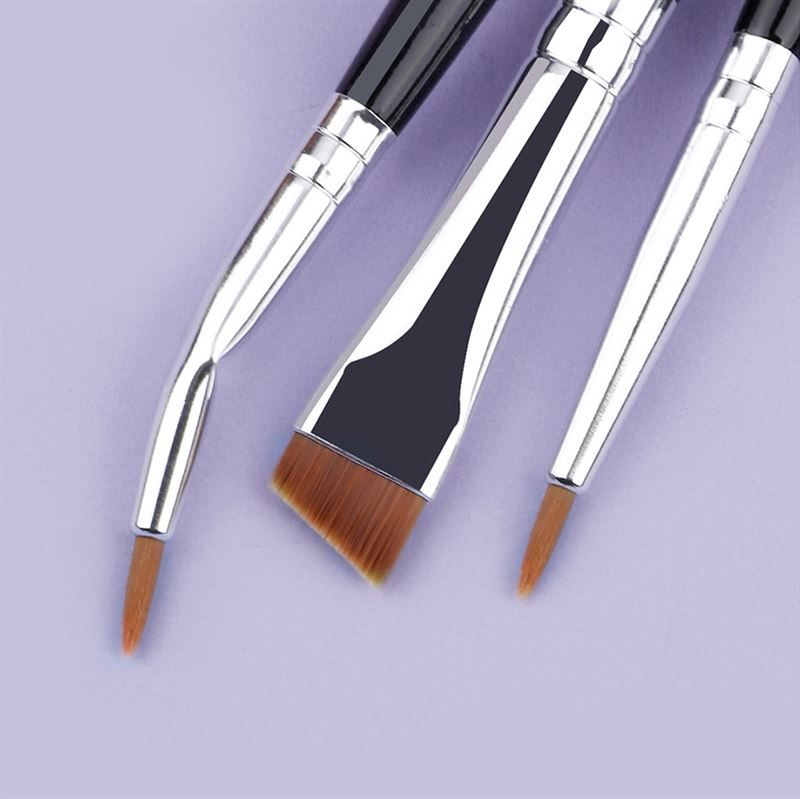 Nahaufnahme von drei Make-up-Pinseln. Schwarze Griffe, silberne Metallhülsen. Verschiedene Pinselköpfe: abgewinkelt, spitz, abgeschrägt.