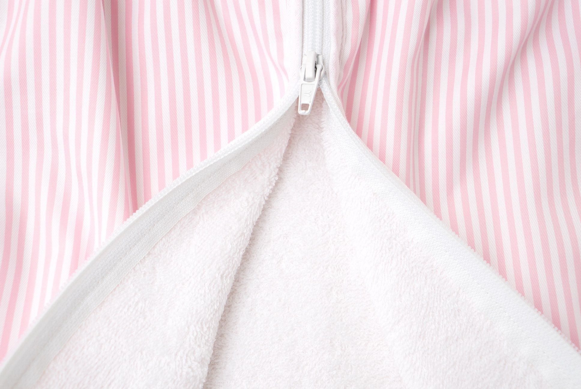 Nahaufnahme des Reißverschlusses eines rosa gestreiften Schlafsacks. Innen weißes Frottee.