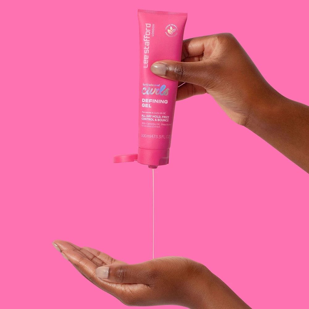 Hand drückt Lee Stafford For The Love Of Curls Defining Gel aus einer rosa Tube in die Handfläche.