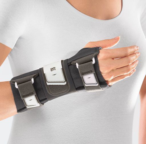 Nahaufnahme der L&R Cellacare® Manu Control Comfort Handgelenkorthese am Handgelenk. Graue Farbe mit weißen Verschlüssen.