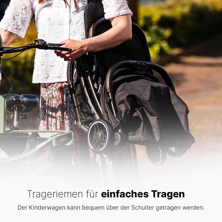 Schwarzer, gefalteter Kinderwagen wird über der Schulter getragen. Text: Trageriemen für einfaches Tragen.