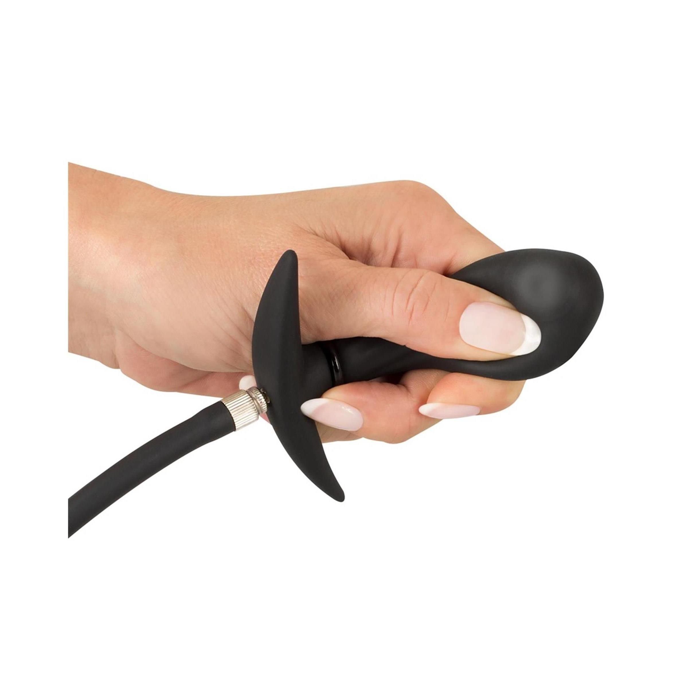 Hand hält schwarzen, aufblasbaren Plug. T-förmiger Griff und Schlauchanschluss sichtbar.