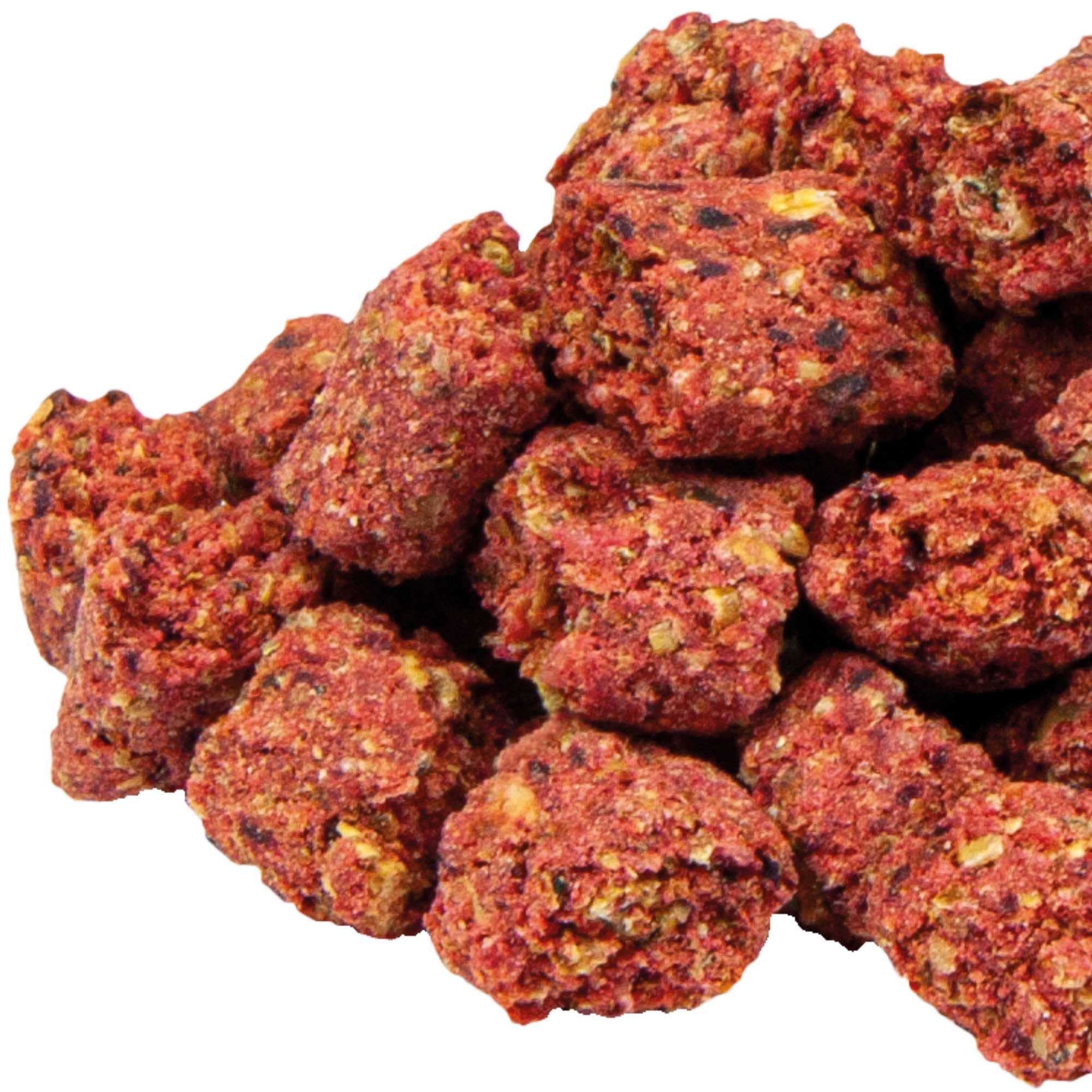 Nahaufnahme von roten, unregelmäßig geformten Hundesnacks. Die Snacks weisen eine körnige Textur auf.