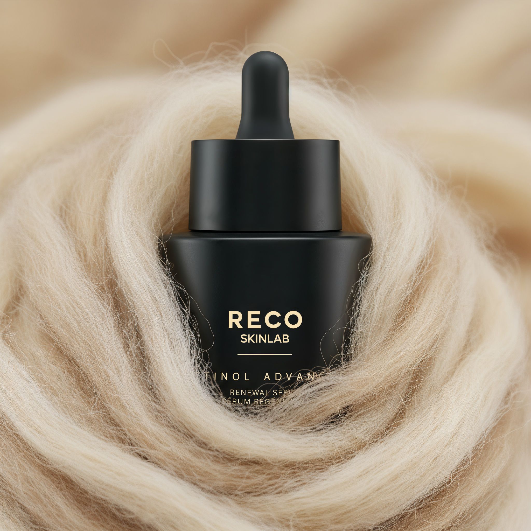 Schwarze Serumflasche mit Pipette auf hellem, flauschigem Hintergrund. Aufschrift: RECO SKINLAB, Retinol Advanced.