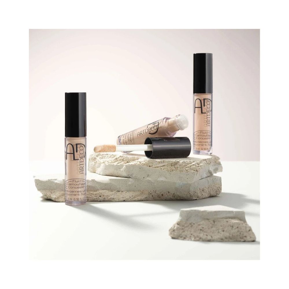 ARTDECO Concealer Fluid Camouflage, Flakons und Applikator auf Steinen arrangiert.