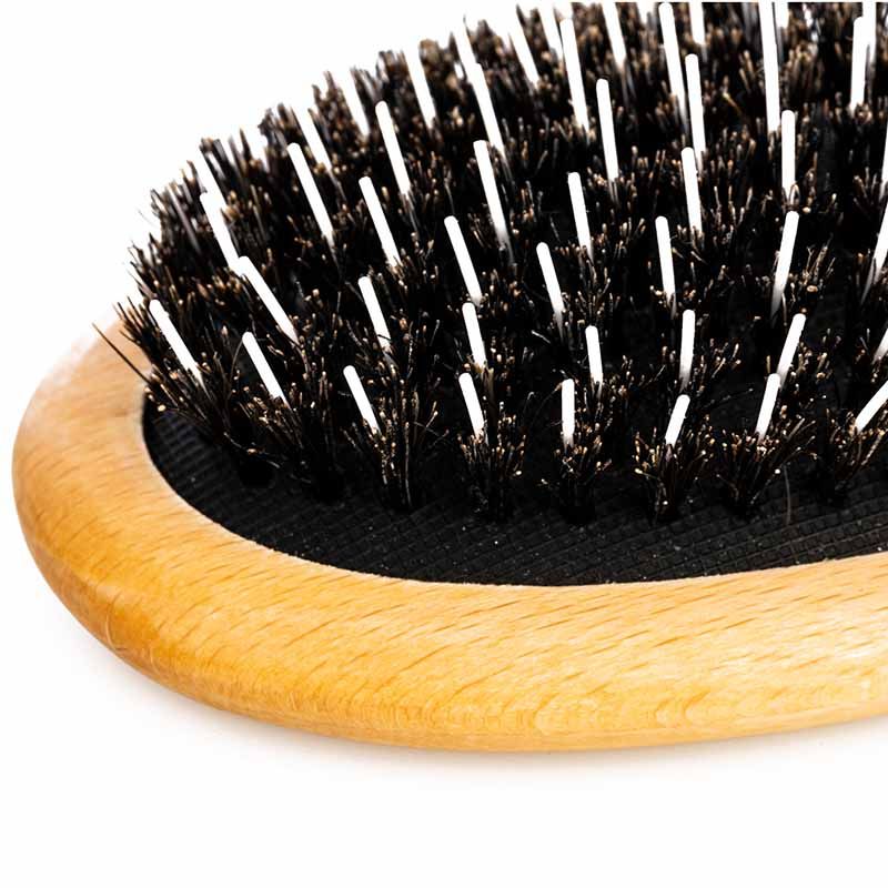 Nahaufnahme der Borsten und des Holzrands einer ovalen Haarbürste mit Wildschweinborsten.