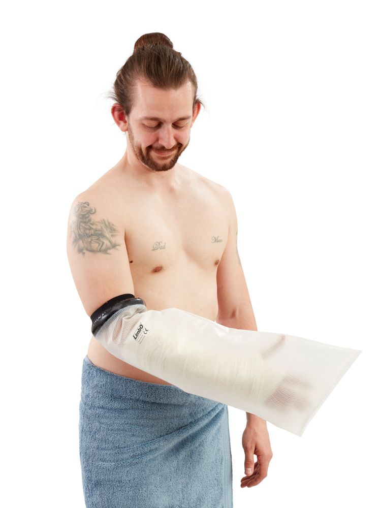 Schutzhülle für Gipsverband, halber Arm, am Arm einer Person. Schwarzer Abschluss, transparente Hülle. Person mit Tattoo und Handtuch.