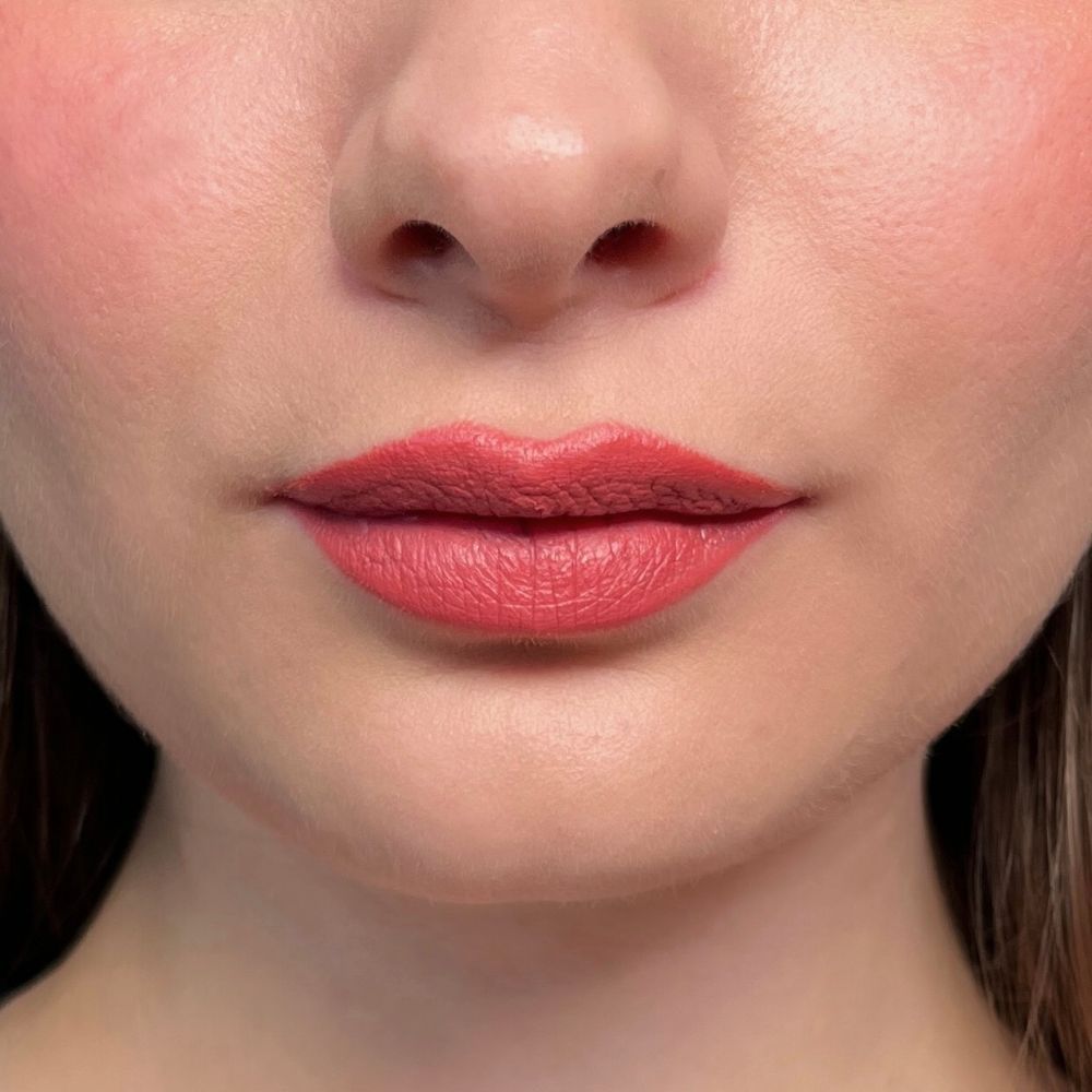 Nahaufnahme von Lippen mit rosa Lippenstift. Hautfarbener Hintergrund.
