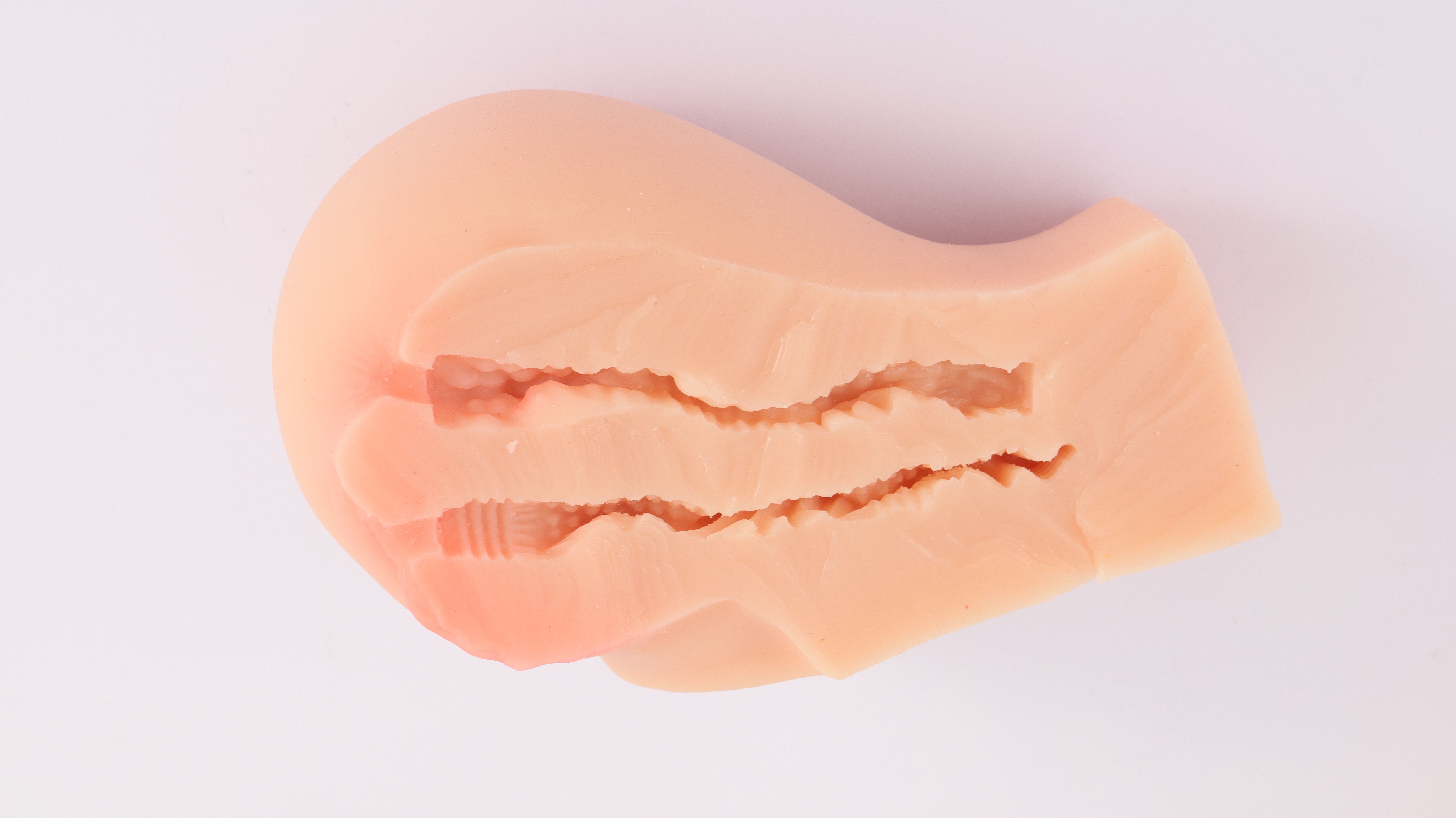 Beige, anatomisch geformtes Produkt mit inneren Rillen. Auf weißem Hintergrund.