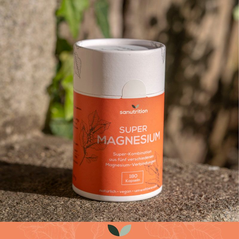 Zylindrische Dose "Sanutrition Super Magnesium" auf Stein. Orangefarbenes Etikett mit Produktinformationen. Natürlicher Hintergrund.