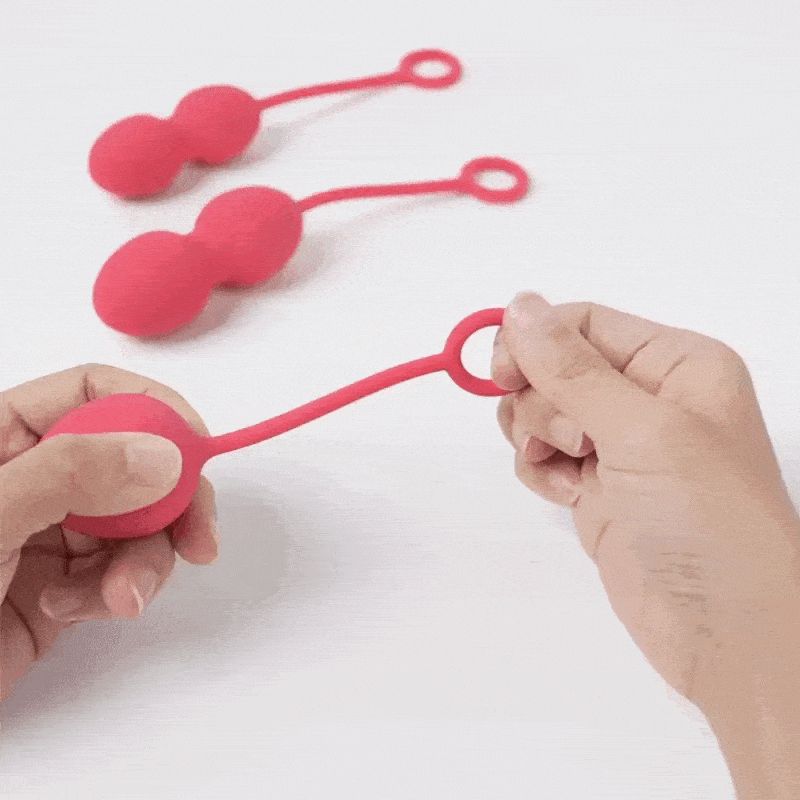 Drei rosafarbene Kegel-Kugeln mit Schlaufen. Eine Kugel wird von einer Hand gehalten.