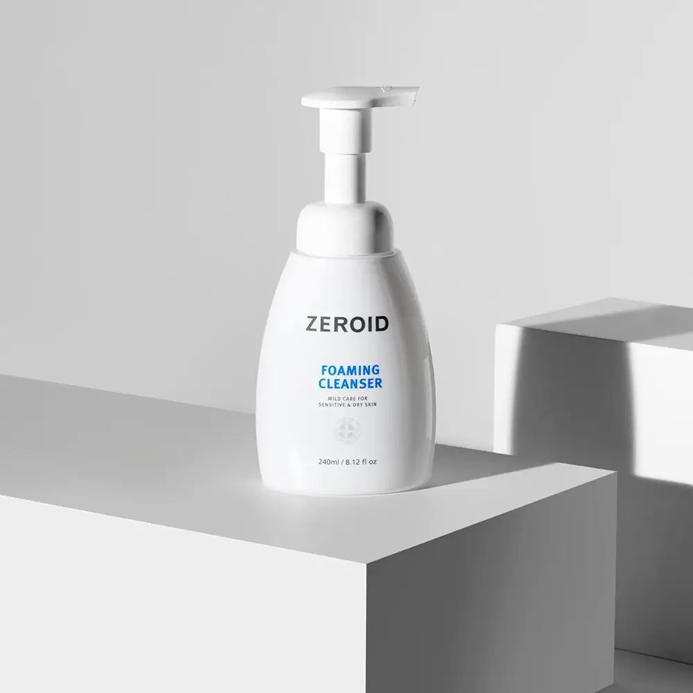 Weiße ZEROID Schaumreiniger-Flasche mit Pumpe auf weißem Podest. Text: FOAMING CLEANSER, mild care for sensitive & dry skin. 240ml/8.12 fl oz.