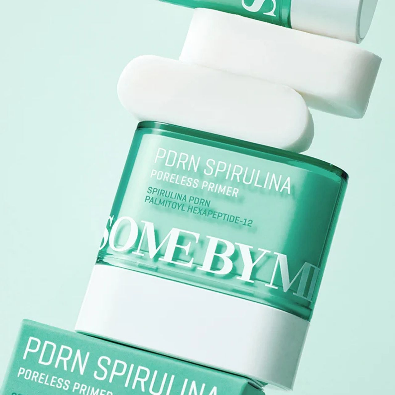 Mehrere SOME BY MI PDRN Spirulina Poreless Primer-Behälter und weiße Stäbchen, gestapelt und schräg angeordnet.