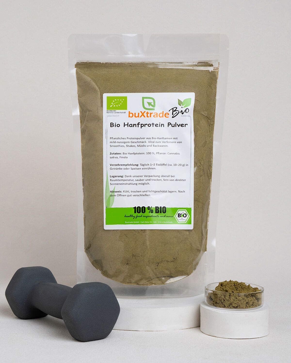 Buxtrade Bio Hanfprotein Pulver neben einer Hantel und einem kleinen Behälter mit Pulver.