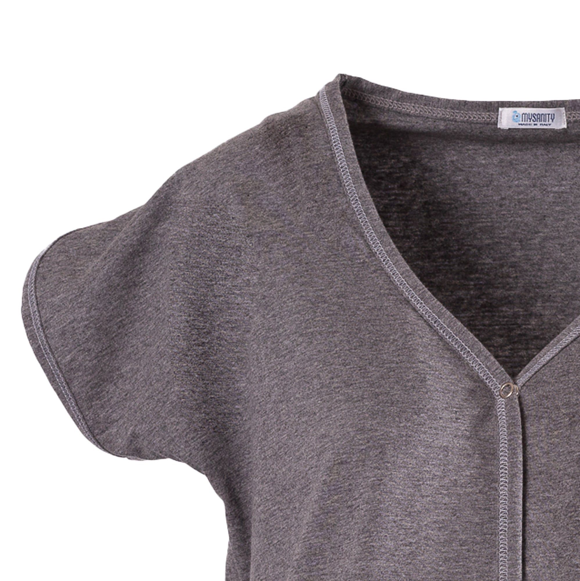 Detailaufnahme des grauen Geburtshemdes. V-Ausschnitt, kurze Ärmel. Kontrastnaht an Ausschnitt und Ärmel. Label.