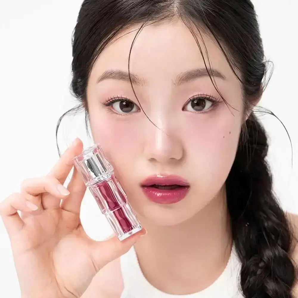 Eine Frau hält einen transparenten Lippenstift mit silberner Kappe, der roten Lippenstift enthält.
