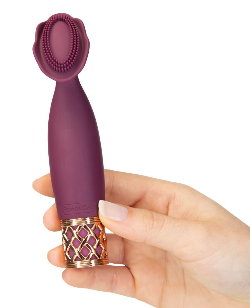 Hand hält lila Vibrator. Goldfarbenes Detail am Ende. Ovale Spitze mit Noppen. Auf weißem Hintergrund.