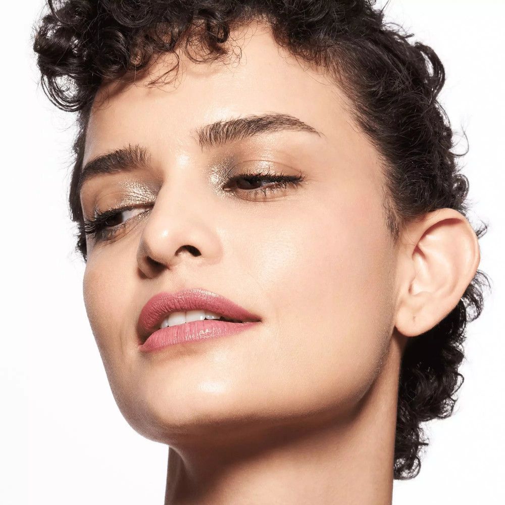 Porträt einer Frau mit Lidschatten. Sie blickt zur Seite und trägt rosafarbenen Lippenstift.