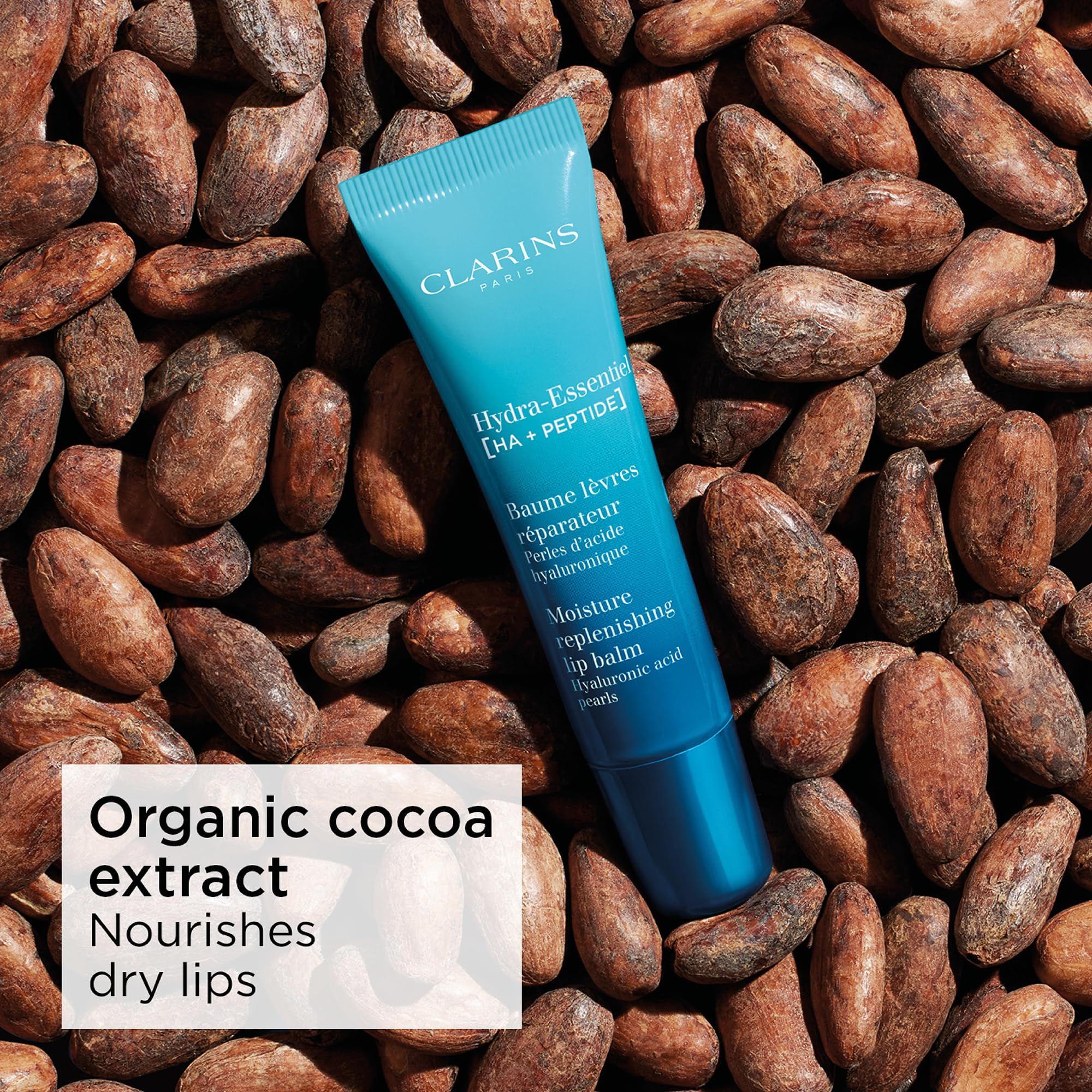 Clarins Hydra-Essentiel Lippenbalsam-Tube auf Kakaobohnen. Text: Organic cocoa extract, Nourishes dry lips.