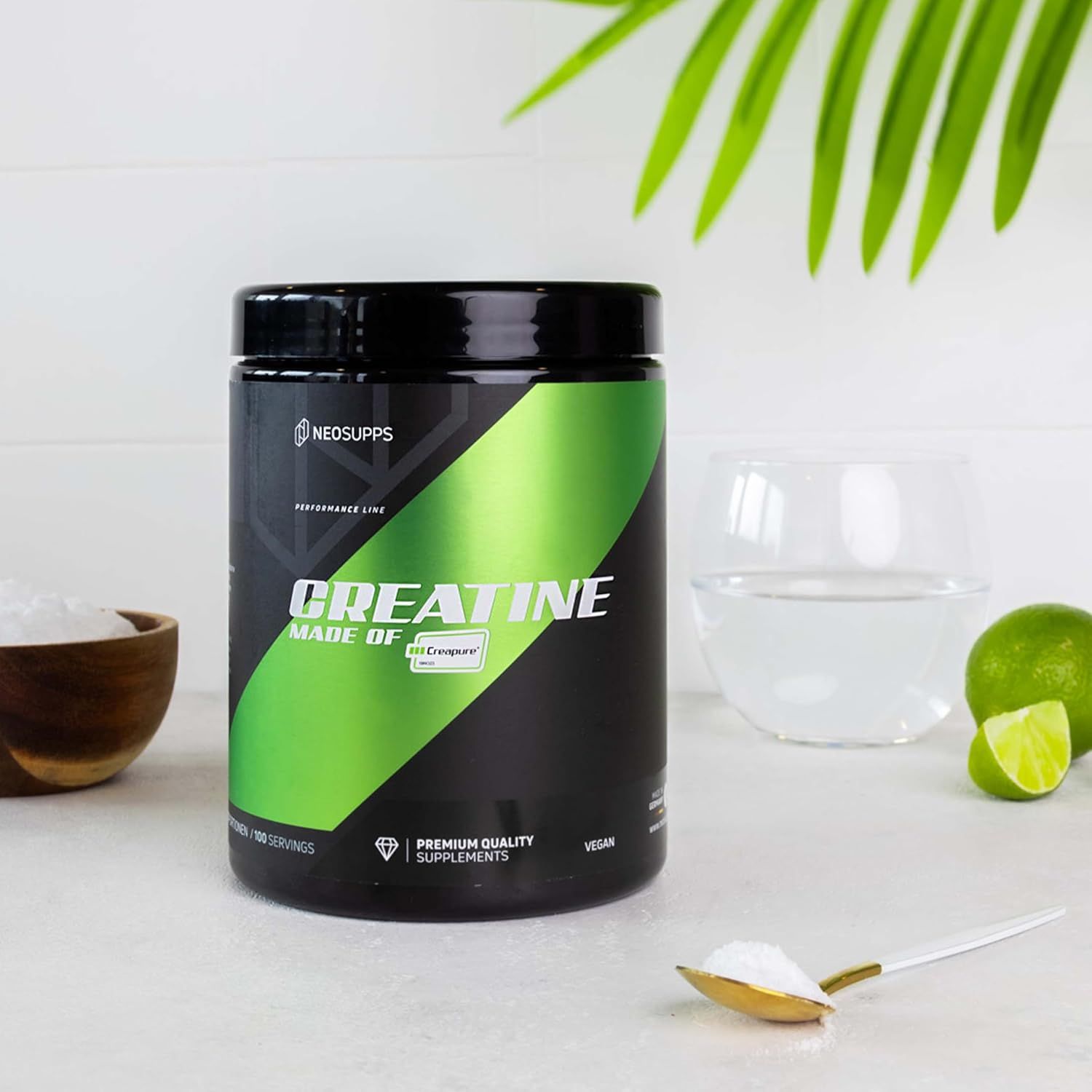 Schwarze Dose mit grünem Streifen. Aufschrift: Creatine Made of Creapure®. Neben: Glas Wasser, Limette, Löffel mit Pulver.