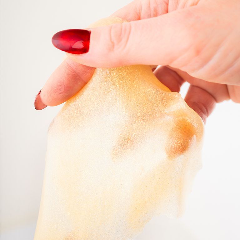 Hand hält Gesichtsmaske. Gelb. Rote Fingernägel. Weißer Hintergrund.