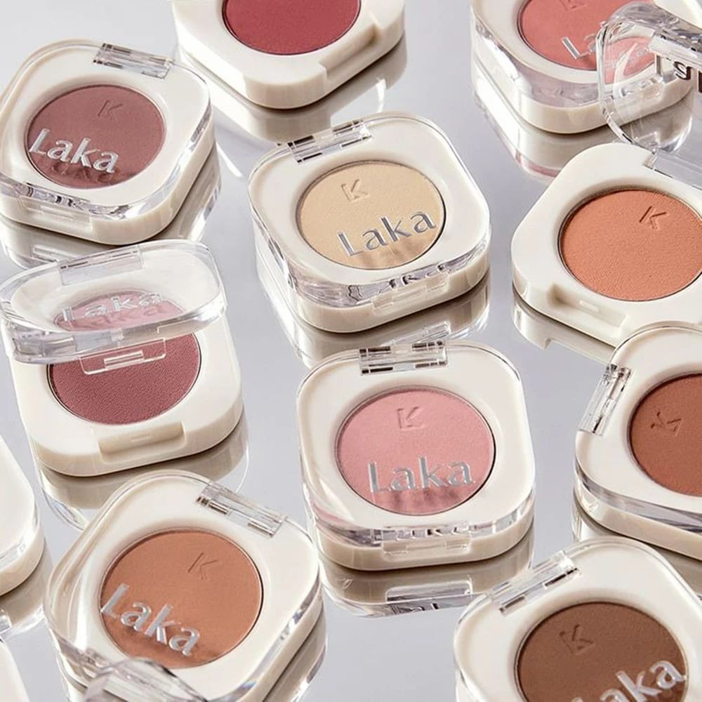 Mehrere Laka Rouge-Produkte in quadratischen, transparenten Behältern mit weißen Rändern und unterschiedlichen Farbtönen.