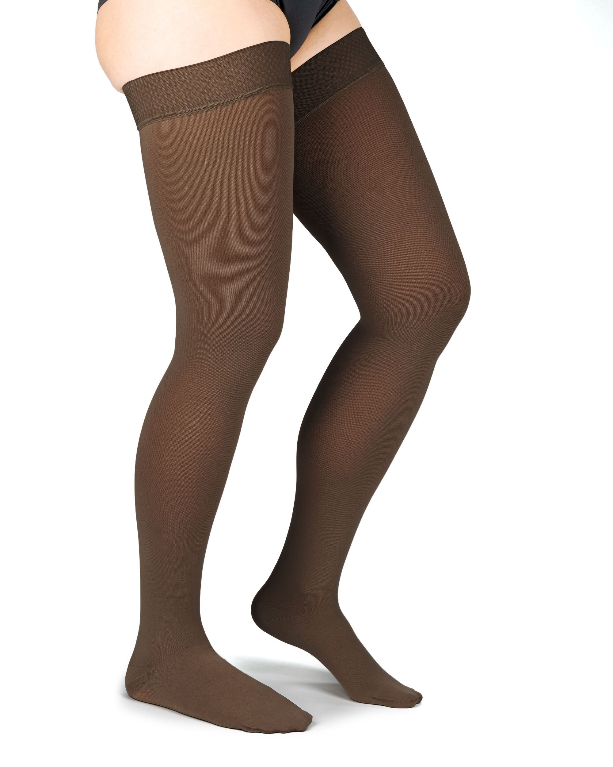 Braune Kompressionsstrümpfe bis zum Oberschenkel. Mit strukturiertem Abschlussband. Blick von der Seite, auf hellem Hintergrund.