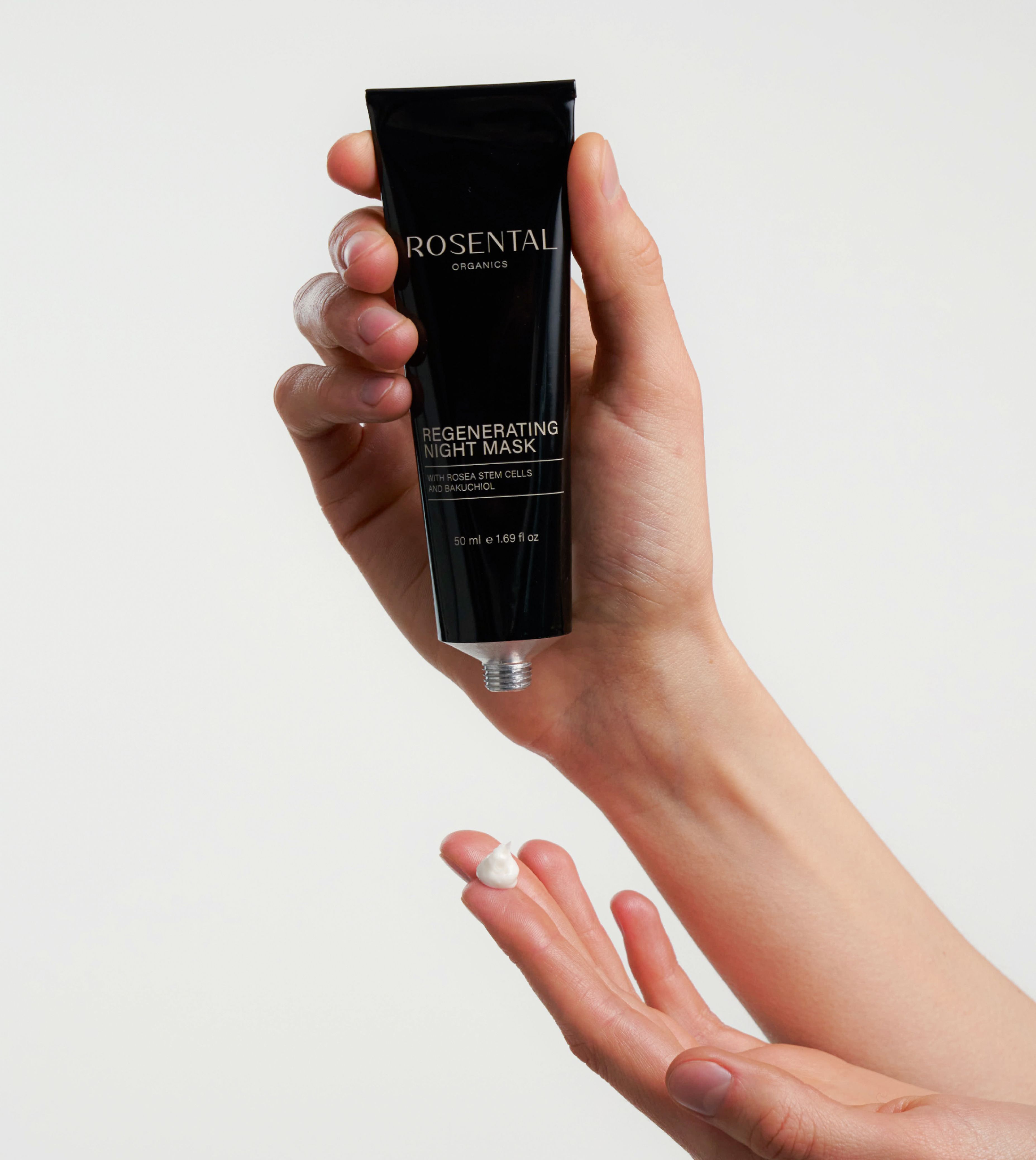 Hand hält Tube mit Regenerating Night Mask. Produkt wird auf die Handfläche gegeben.