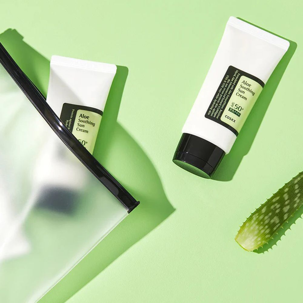 Zwei Tuben mit schwarzem Deckel und Aufschrift: Aloe Soothing Sun Cream, COSRX. Auf grünem Grund.