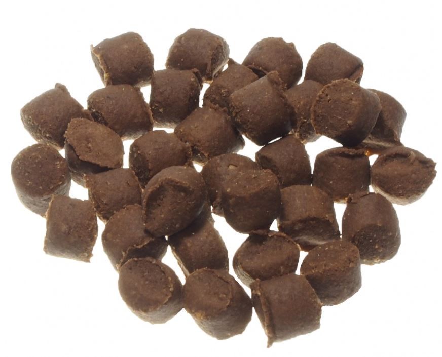 Hundesnack in Form von kleinen, braunen, zylindrischen Stücken. Auf weißem Hintergrund verstreut.