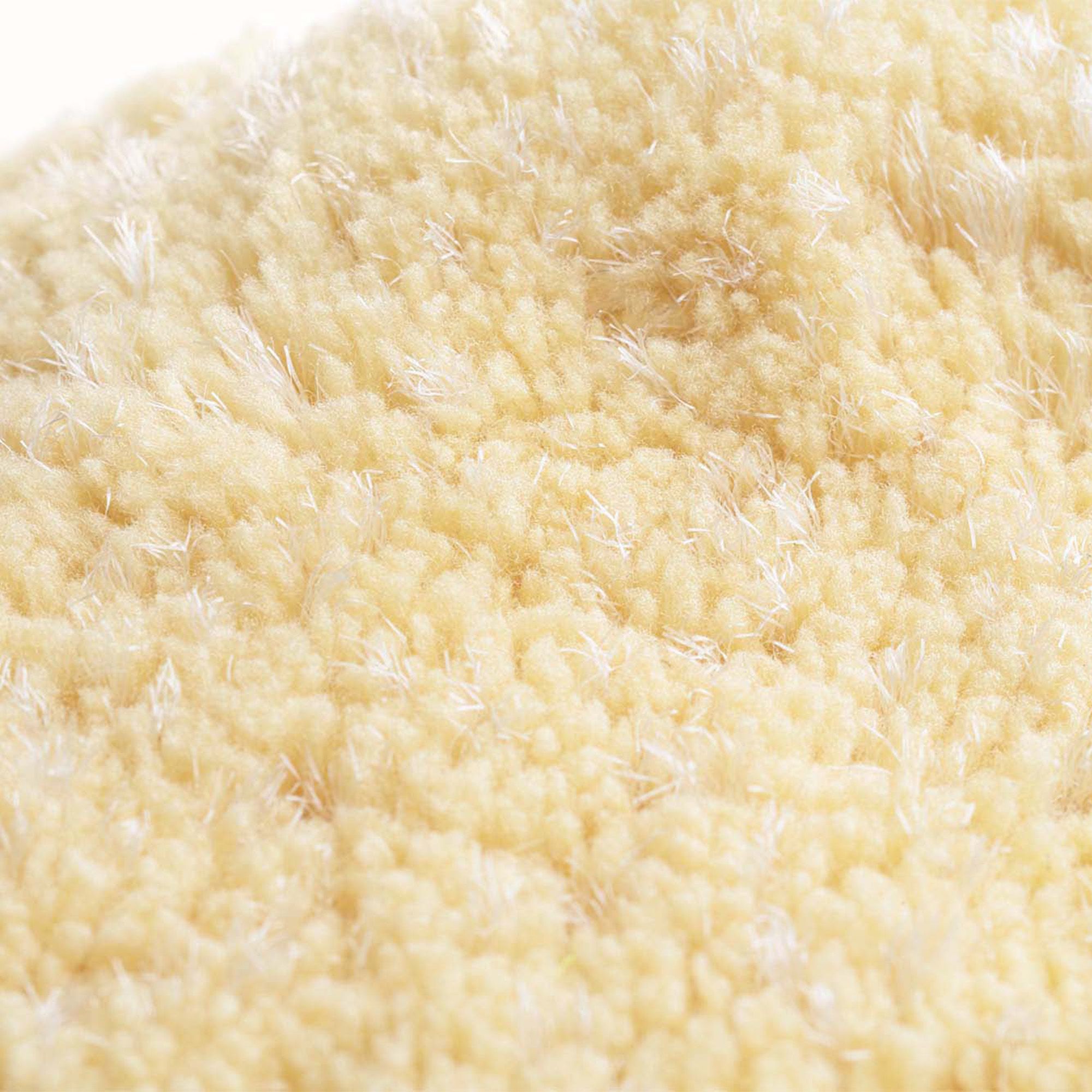 Nahaufnahme eines gelblichen, ovalen Abschminkpads. Textilmaterial mit sichtbarer Struktur.