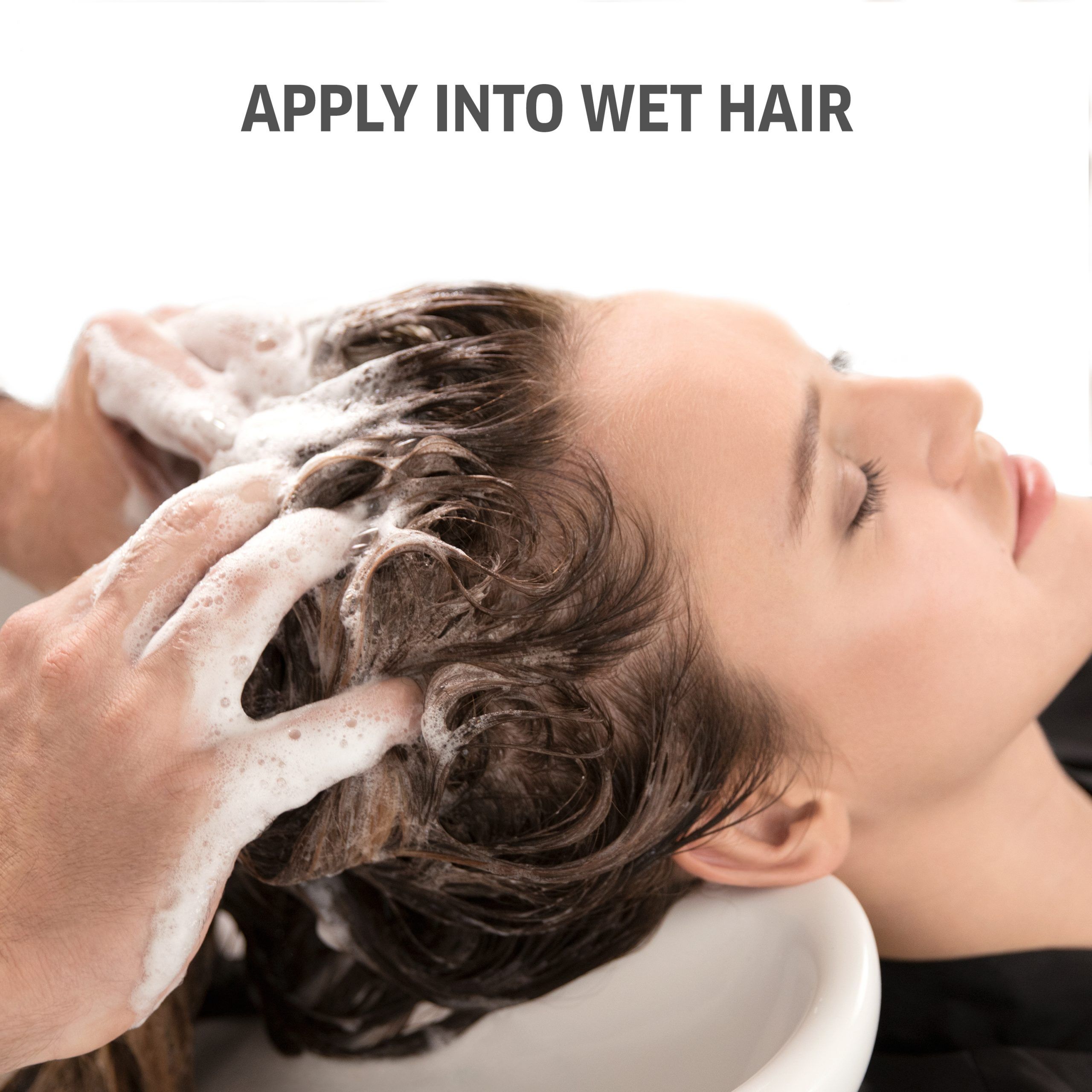 Person wäscht Haare einer Frau. Text: APPLY INTO WET HAIR. Frau liegt in Waschbecken. Schaum auf dem Haar.